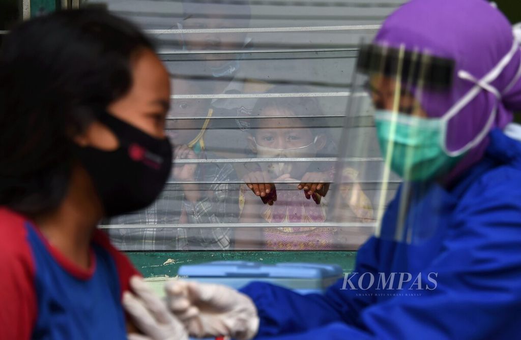 Siswa melihat dari balik kaca temannya yang disuntik vaksin measles rubella (MR) di SD Karunia Hidup, Surabaya, Jawa Timur, Rabu (14/10/2020). Imunisasi MR (untuk kelas 1 dan 5) dan HPV (untuk kelas 6) yang berlangsung selama bulan Oktober menyasar 43.688 anak tingkat sekolah dasar. Walau masih belajar dari rumah, diharapkan imunisasi yang diberikan dapat menjaga kekebalan tubuh siswa di tengah pandemi.