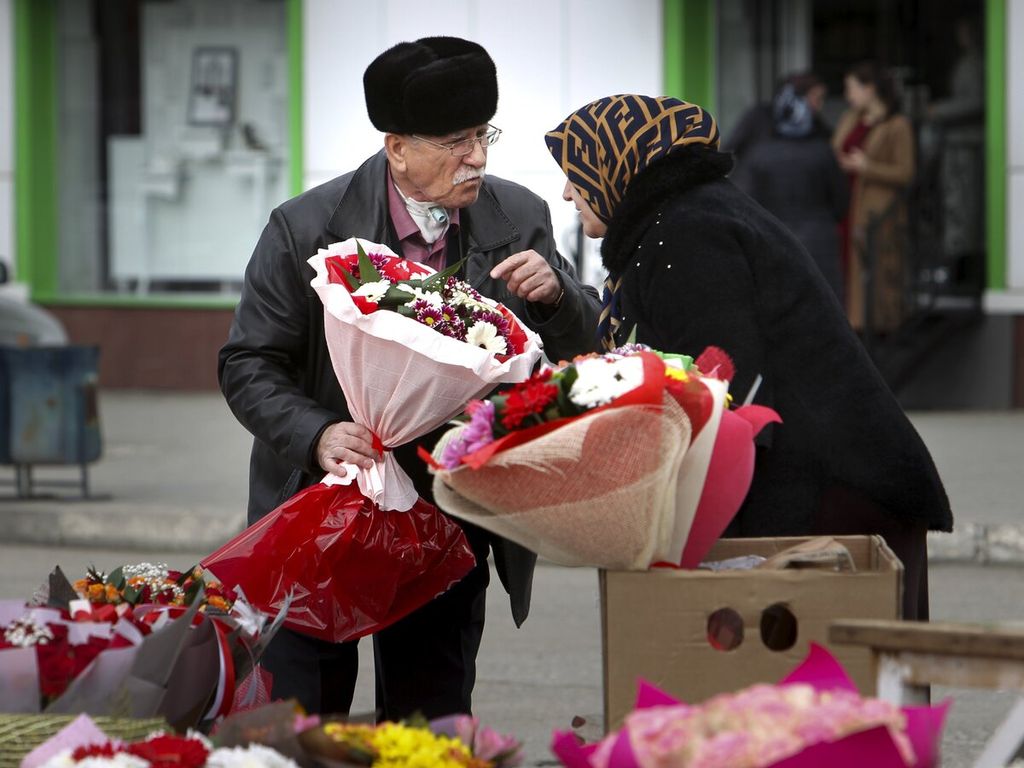 Seorang pria membeli bunga di pasar bunga menjelang Hari Perempuan Internasional di Grozny, Rusia, Minggu, (7/3/2021). 