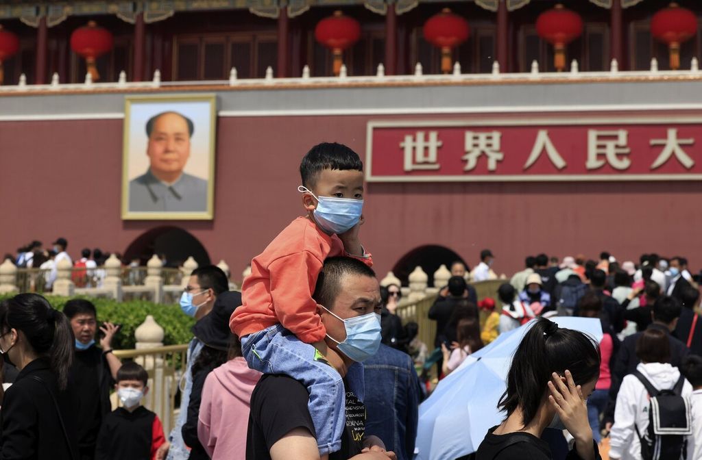 Seorang anak yang memakai masker mengunjungi Gerbang Tiananmen, Beijing, China. Tampak pada latar belakang potret Mao Zedong, pemimpin revolusi China. 