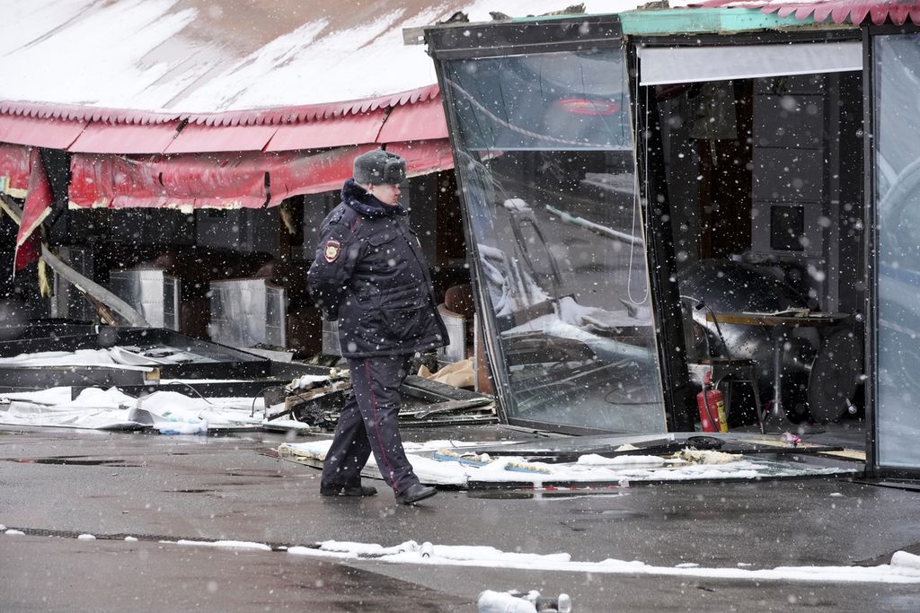 Seorang polisi berjalan di dekat lokasi ledakan bom di kafe  "Street Bar"di St. Petersburg, Rusia, Senin (3/4/2023). (AP Photo/Dmitri Lovetsky)