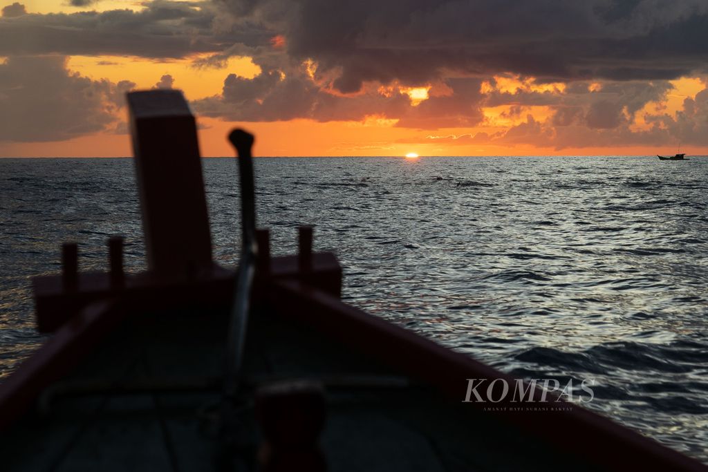 Perahu kayu Rustam (48) bergerak pulang saat matahari terbenam setelah menangkap ikan tongkol di perairan yang berjarak sekitar 45 kilometer di sebelah timur Pulau Natuna Besar, Kepulauan Riau, Sabtu (26/3/2022).