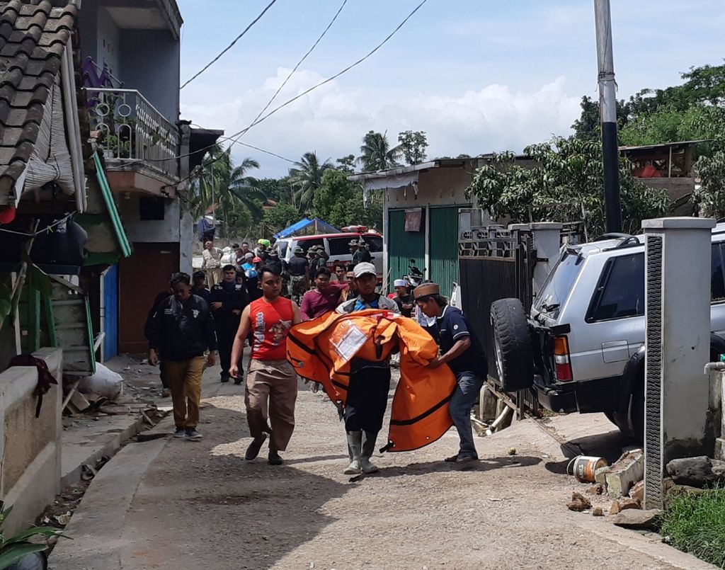 A SAR officer carried the body of Yayan's son (40), at RT 03 RW 01, Selaerih Village, Genjot Village, Cugenang, Cianjur Regency, Tuesday (22/11/2022).