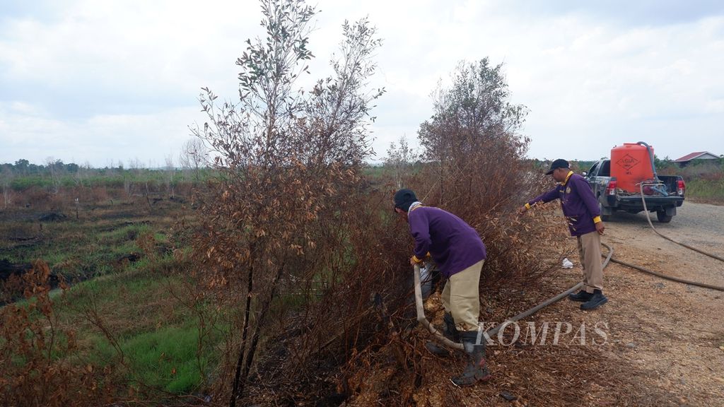 Personel penanggulangan kebakaran hutan dan lahan membasahi lahan gambut yang masih berasap di Guntung Damar, area sekitar Bandar Udara Syamsudin Noor di Banjarbaru, Kalimantan Selatan, Senin (7/10/2019). 