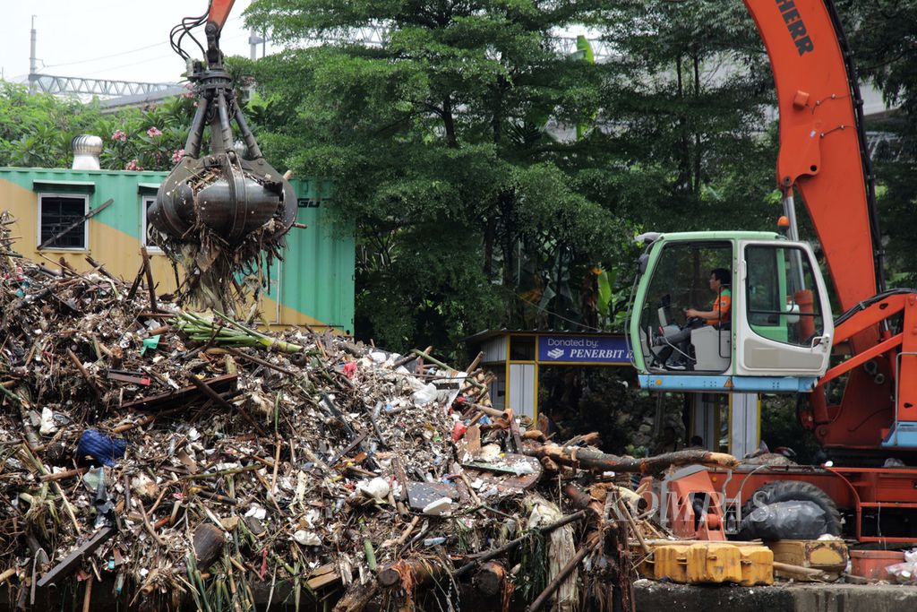 Alat berat digunakan untuk mengangkat sampah yang tersangkut di Pintu Air Manggarai, Jakarta, Senin (10/10/2022). Sampah ini terbawa aliran air Sungai Ciliwung. 