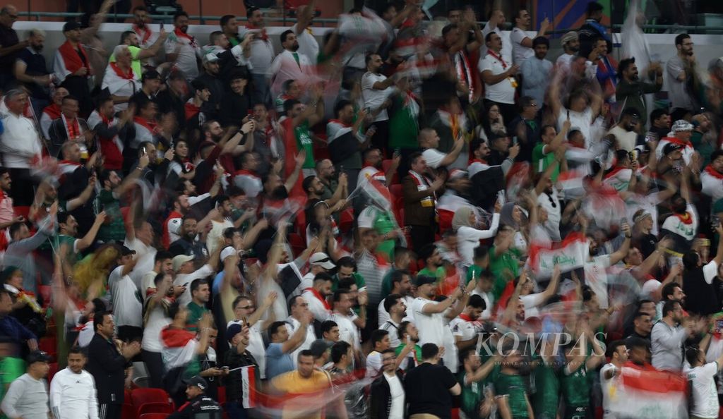 Suporter Irak mengibarkan bendera saat mendukung tim Irak melawan Indonesia pada pertandingan Grup D Piala Asia 2023 di Stadion Ahmed bin Ali, Qatar, Senin (15/1/2024). Indonesia ditaklukkan Irak dengan skor 1-3.