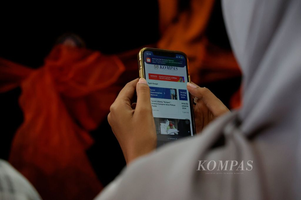 Mahasiswa membuka <i>Kompas</i> digital dengan mengunjungi laman Kompas.id melalui telepon selulernya dalam acara seminar literasi digital di Auditorium FISIP Universitas Diponegoro, Kota Semarang, Jawa Tengah, Rabu (24/5/2023). 