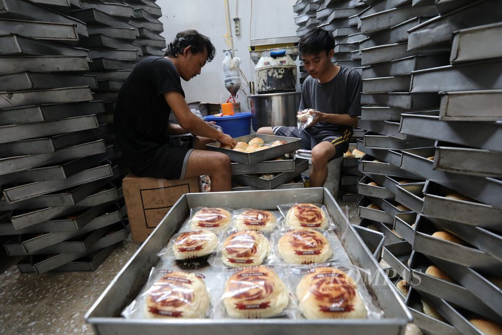 Pekerja mengemas roti di pabrik skala rumahan di kawasan Kebon Nanas, Jakarta Selatan, Senin (16/1/2023). Produsen memasok roti berbahan terigu tersebut ke sekitar 400 warung, pedagang roti keliling, dan kantin sekolahan. 