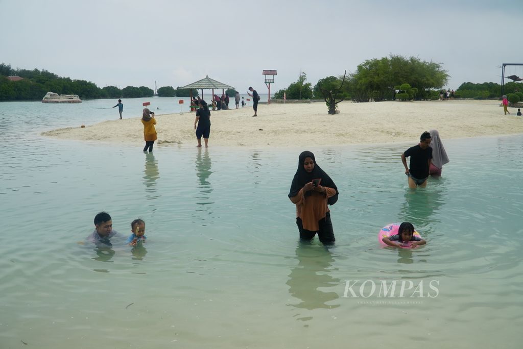Wisatawan bermain di Pantai Pasir Perawan di Pulau Pari, Kabupaten Administrasi Kepulauan Seribu, Jakarta, Senin (1/1/2024). 