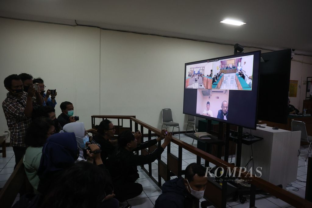 Sejumlah jurnalis memotret mantan Wali Kota Yogyakarta Haryadi Suyuti (mengenakan peci) yang tampak pada layar di ruang sidang Pengadilan Negeri Yogyakarta, DI Yogyakarta, saat mengikuti sidang secara daring , Selasa (28/2/2023). 