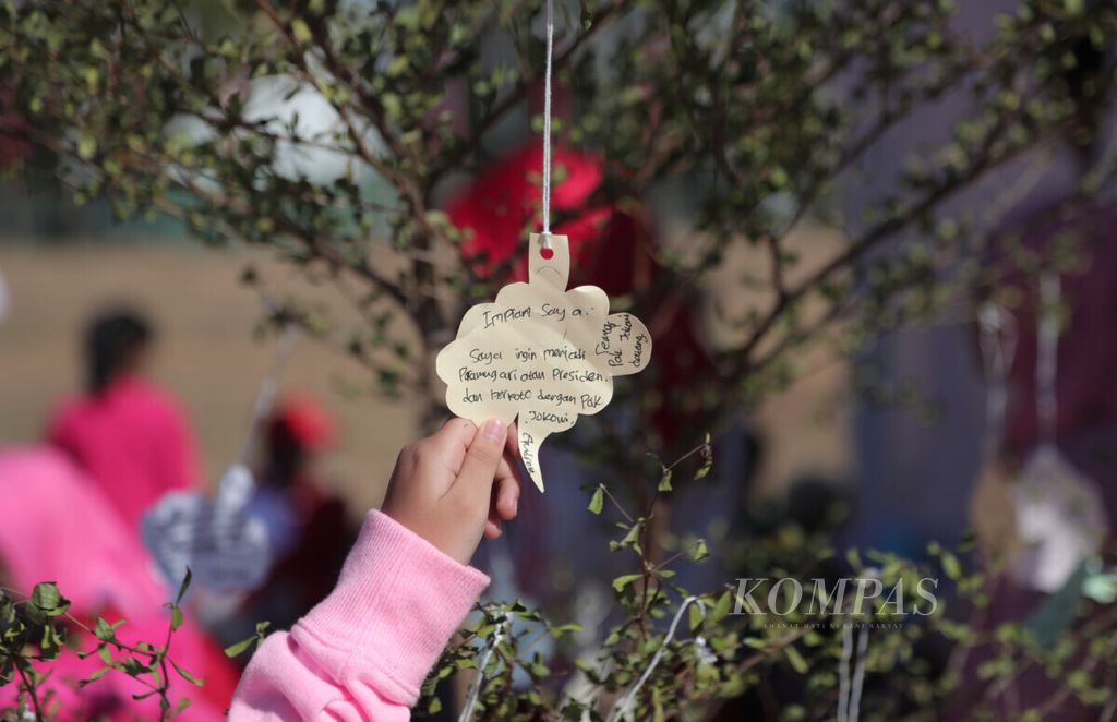 Seorang anak menunjukkan kertas berisi harapan dan cita-citanya yang tergantung di Pohon Harapan yang terdapat dalam puncak peringatan Hari Anak Nasional 2019 yang digelar di Lapangan Karebosi, Makassar, Sulawesi Selatan, Selasa (23/7/2019). 