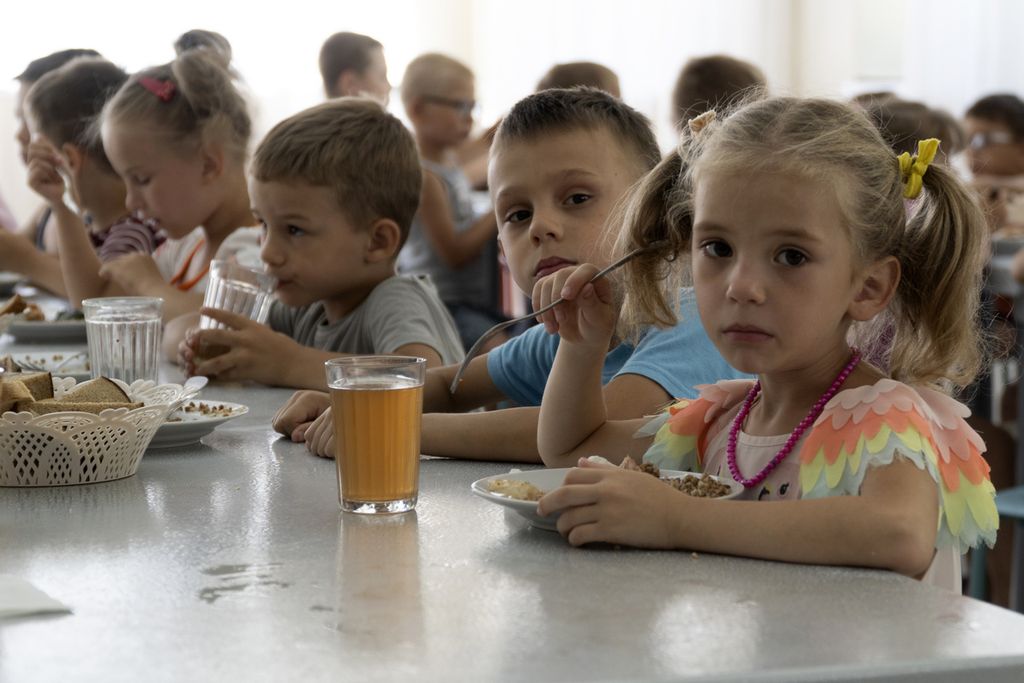 Anak-anak dari sebuah panti asuhan di wilayah Donetsk menyantap makanan di kamp Zolotaya Kosa, dekat Laut Azov, wilayah Rostov, Rusia barat daya, 8 Juli 2022. 