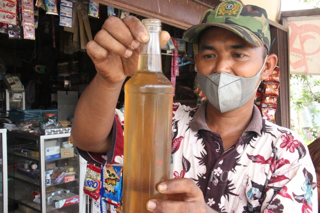 Jupriadi (32), warga pesisir di Kecamatan Segedong, Kabupaten Mempawah, Kalimantan Barat, menunjukkan sebotol minyak kelapa yang diolah ibunya, April lalu.