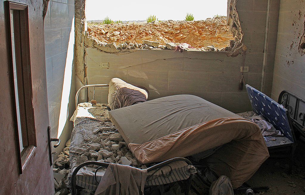Tempat tidur rumah sakit di Al-Tahh, Provinsi Idlib, Suriah, berantakan tertutup puing dari dinding kamar yang hancur, Selasa (19/9), setelah serangan udara yang dilakukan pasukan Pemerintah Suriah.