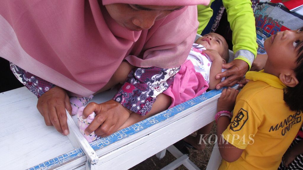 Petugas posyandu, Rahardjo, di Desa Savanajaya, Kecamatan Waeapo, Kabupaten Buru, Maluku, mengukur tinggi badan anak, Jumat (11/5/2018). Posyandu memiliki peran penting dalam meningkatkan derajat kesehatan ibu dan anak.