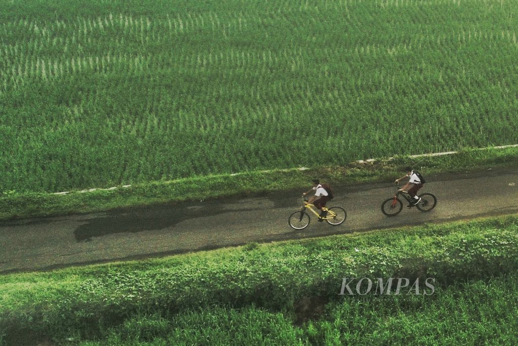 Murid sekolah dasar bersepeda menuju sekolah melintasi areal persawahan di kawasan Kembang, Pacitan, Jawa Timur, Senin (9/5/2022). Kegiatan belajar mengajar secara tatap muka kembali dilaksanakan seusai libur lebaran. 