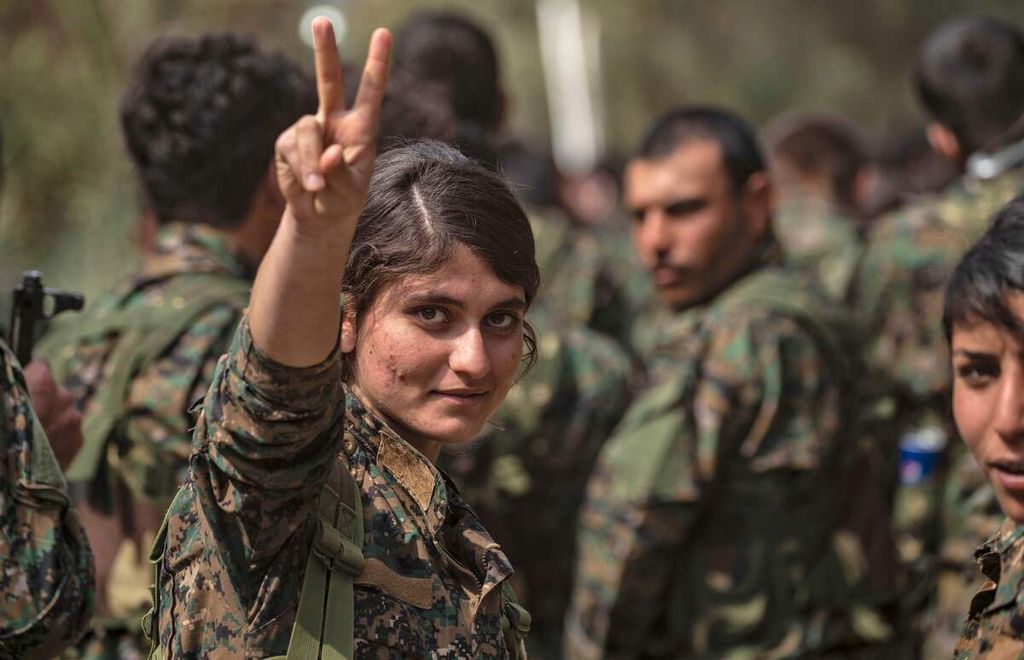 Seorang perempuan petempur anggota milisi Pasukan Demokratik Suriah (SDF) Kurdi dukungan AS mengacungkan isyarat tangan berisi pesan ”kemenangan (<i>victory</i>)” di dekat ladang minyak Omar di Provinsi Deir Ezzor, Suriah timur, 23 Maret 2019. 