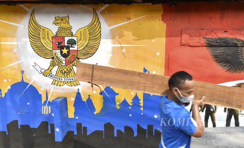 Warga melintas di depan mural Pancasila di kawasan Galur, Jakarta Pusat, Kamis (29/7/2021). Nilai-nilai yang terkandung dalam Pancasila sebagai dasar dan ideologi negara harus terus dilestarikan dalam kehidupan sehari-hari dari generasi ke generasi. 