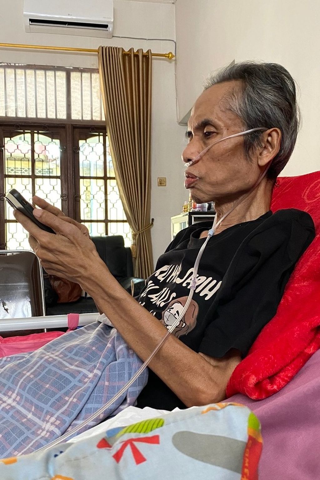 Penyair Joko Pinurbo mencoba melihat pesan-pesan dalam telepon genggamnya, Senin (22/1/2024), di kediamannya di Yogyakarta.