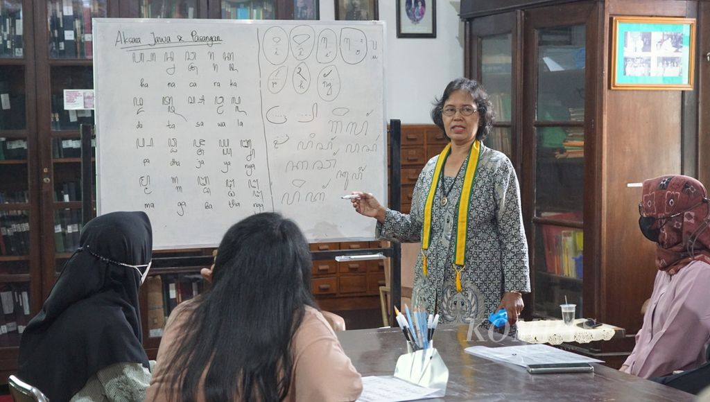 Seorang pengajar memberikan materi aksara Jawa kepada wisatawan, di Pura Mangkunegaran, Kota Surakarta, Jawa Tengah, Kamis (29/12/2022). Itu merupakan atraksi budaya tambahan yang disuguhkan pengelola pura bagi wisatawan semasa libur akhir tahun 2022.
