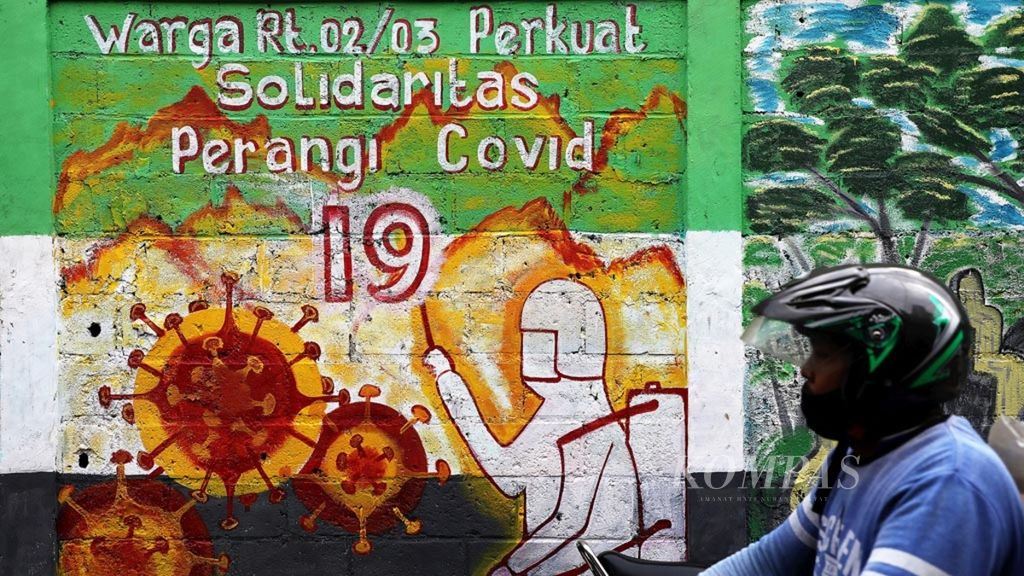 A male rider passes a mural with an invitation to build solidarity in the fight against Covid-19 on the wall of a building in Pondok Aren, South Tangerang, Banten, Sunday (05/10/2020).