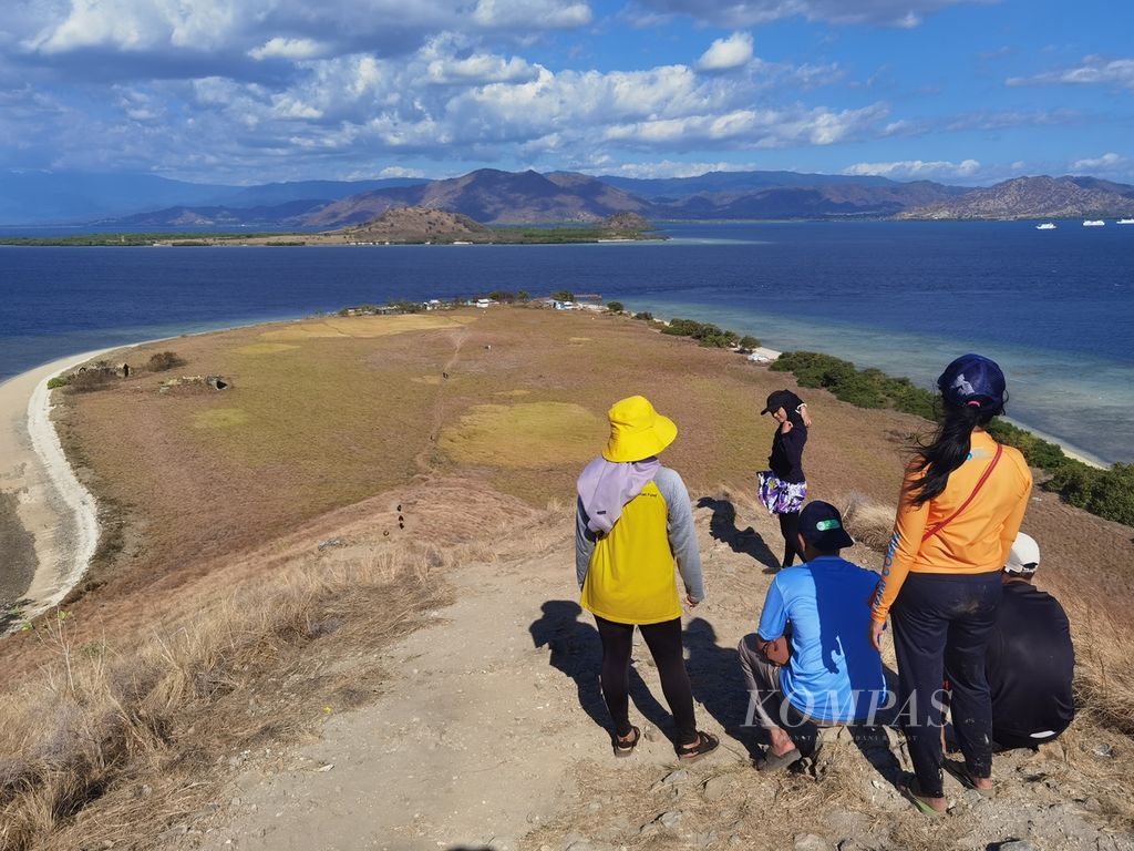 Wisatawan menikmati keindahan lanskap Pulau Kenawa dari puncak bukit Kenawa di Kawasan Konservasi Taman Wisata Perairan Gili Balu, Kecamatan Poto Tano, Kabupaten Sumbawa Barat, NTB, Senin (17/7/2023).