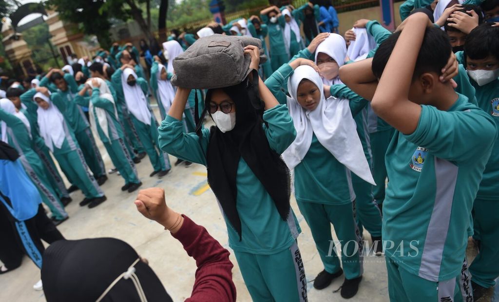 Siswa berkumpul di lapangan sekolah untuk dilakukan pendataan saat simulasi penanganan bencana gempa bumi di SMPN 27 Surabaya, Kota Surabaya, Selasa (29/11/2022). 