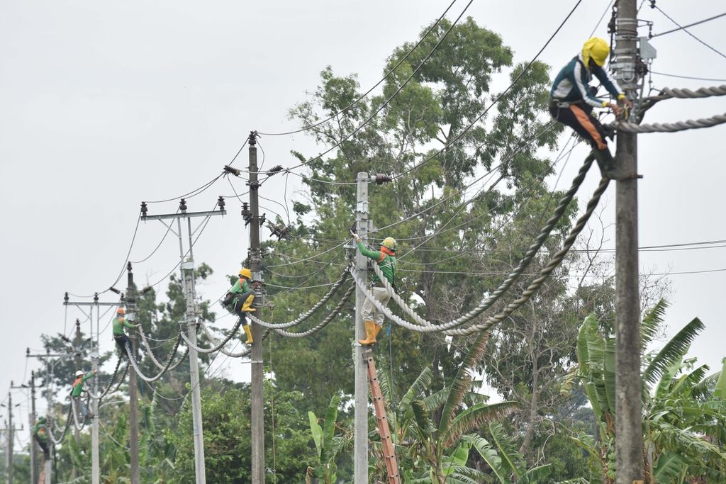 Petugas PLN menyelesaikan pemasangan saluran kabel udara tegangan menengah (SKUTM) di Desa Bangak, Banyudono, Boyolali, Jawa Tengah, Minggu (29/12/2019). 