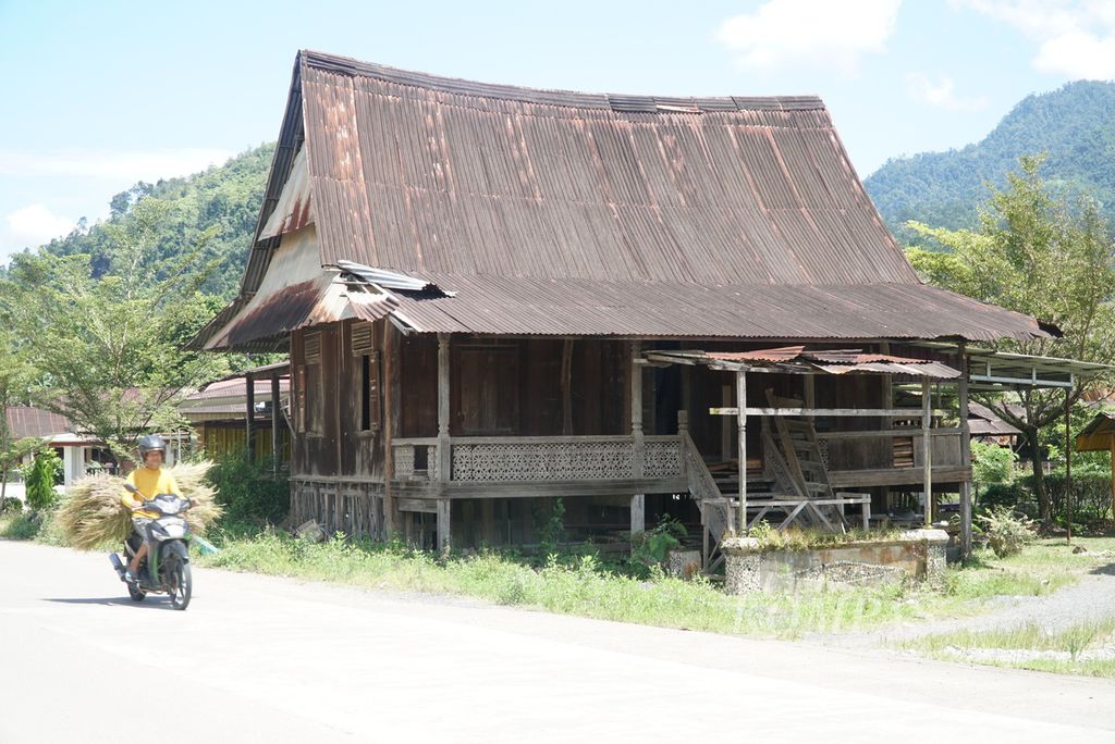 Warga melintas di sebelah Rumah Gadang Kajang Padati yang sudah tidak dihuni dan mulai rusak di Kelurahan Gunung Sarik, Kecamatan Kuranji, Kota Padang, Sumatera Barat, Selasa (11/10/2022). 
