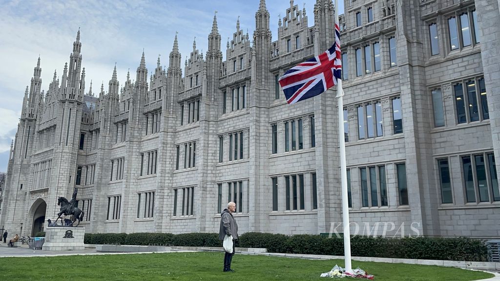 Michael Painter (68) berdiri di depan tiang bendera di Marischal College, Aberdeen, Skotlandia, Jumat (9/9/2022). Dia merasa sedih atas kepergian Ratu Elizabeth II, terutama karena dirinya terlibat dengan komunitas yang berkaitan dengan Commonwealth.