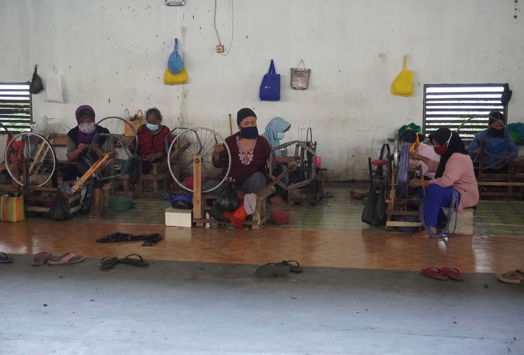 Para pekerja memintal benang yang akan ditenun menggunakan alat tenun bukan mesin menjadi sarung di Desa Wangandawa, Kecamatan Talang, Kabupaten Tegal, Sabtu (24/4/2021). 