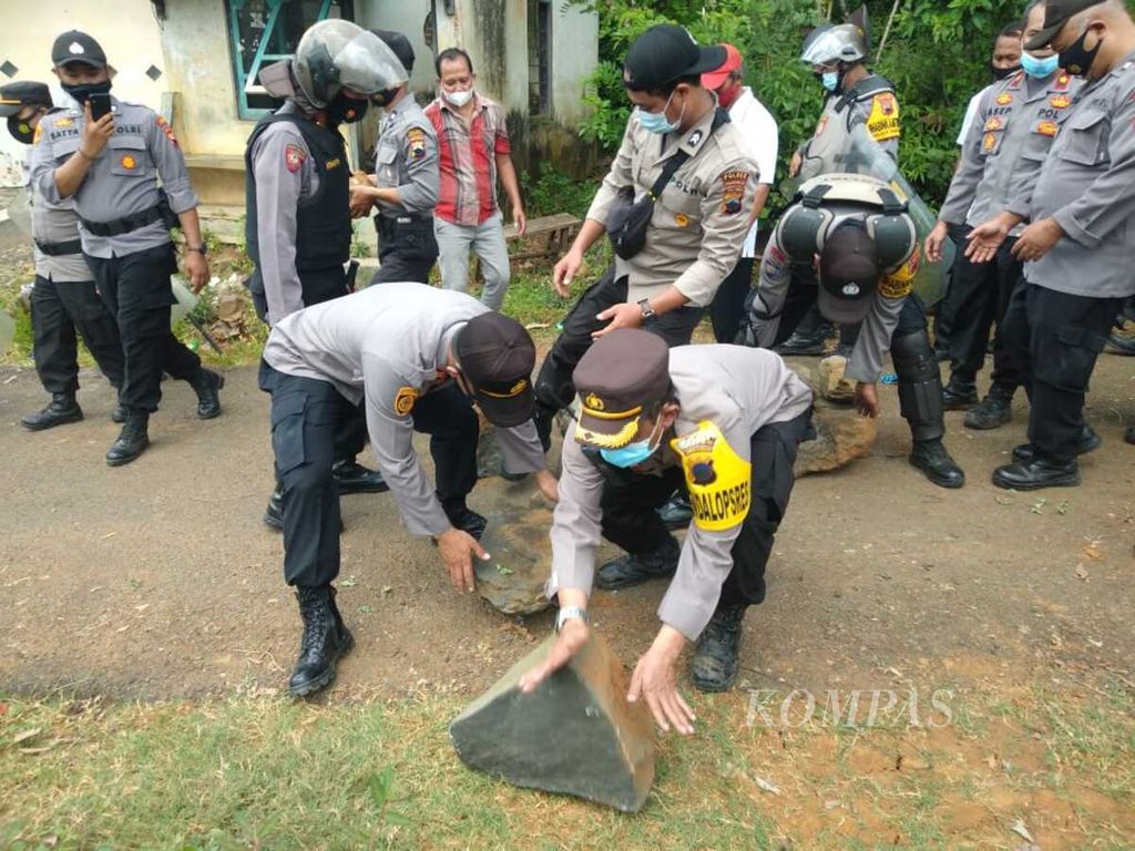Jajaran anggota Polres Purworejo membersihkan batu yang digunakan warga Desa Wadas untuk memblokade jalan, di Desa Wadas, Kecamatan Bener, Kabupaten Purworejo, Jawa Tengah, Jumat (24/4/2021). 