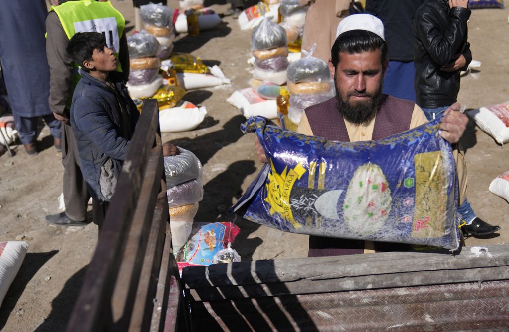 Seorang laki-laki Afghanistan memegang sekarung beras saat pembagian bantuan pangan bagi warga miskin di Kabul, 16 Februari 2022.