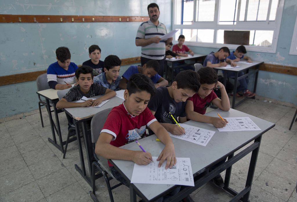Dalam arsip foto tanggal 26 Mei 2019 ini, seorang guru mengawasi anak-anak sekolah Palestina mengikuti ujian akhir di Badan Bantuan dan Pekerjaan PBB untuk Pengungsi Palestina di Timur Dekat, UNRWA, Hebron Boys School, di kota Hebron, Tepi Barat. 