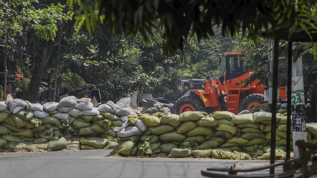 Alat berat digunakan untuk memindahkan karung pasir yang dipasang pengunjuk rasa antikudeta militer sebagai barikade untuk melindungi mereka karena aparat keamanan di Mandalay, Mynamar, Kamis (18/3/2021).