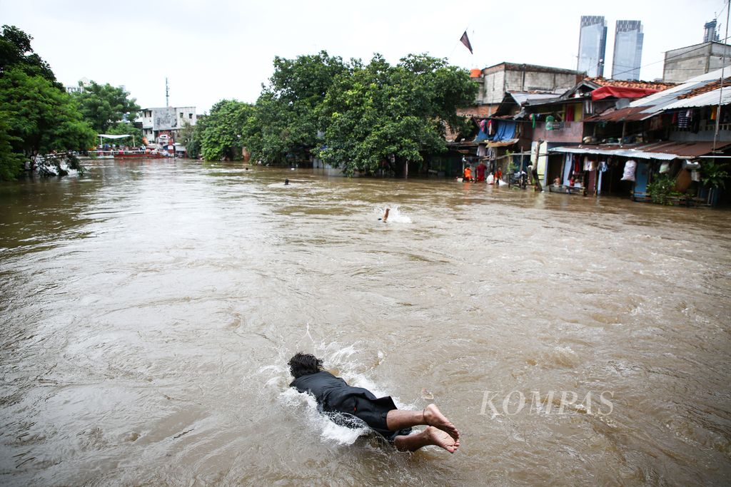 ILUSTRASI. Warga melompat ke Kali Krukut yang meluap di Kelurahan Karet Tengsin, Tanah Abang, Jakarta Pusat, Selasa (25/2/2020).
