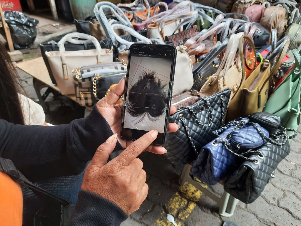 Pedagang rambut palsu, Sri Rejeki (52) menunjukkan contoh wig dari rambut asli yang dijual di Pasar Baru, Jakarta, Jumat (17/2/2023). Meski demikian, penyintas kanker yang jadi pelanggannya lebih memilih wig sintetis karena harganya lebih terjangkau.