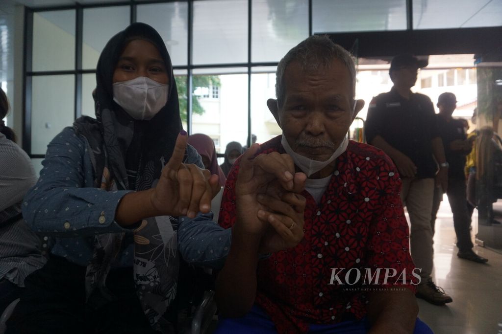 Eji (28) dan Kusmaedi (71) menunjukkan jarinya yang telah dicelupkan ke tinta setelah pencoblosan di RSUD Margono, Purwokerto, Banyumas, Jawa Tengah, Rabu (14/2/2024).