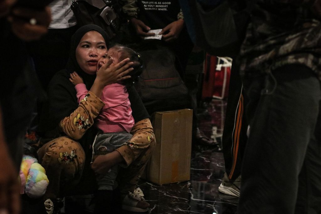 Seorang pemudik menenangkan anak yang menangis di Pelabuhan Merak, Cilegon, Banten, Kamis (20/4/2023). Puncak arus mudik Lebaran masih terlihat di Pelabuhan Merak saat dini hari. 