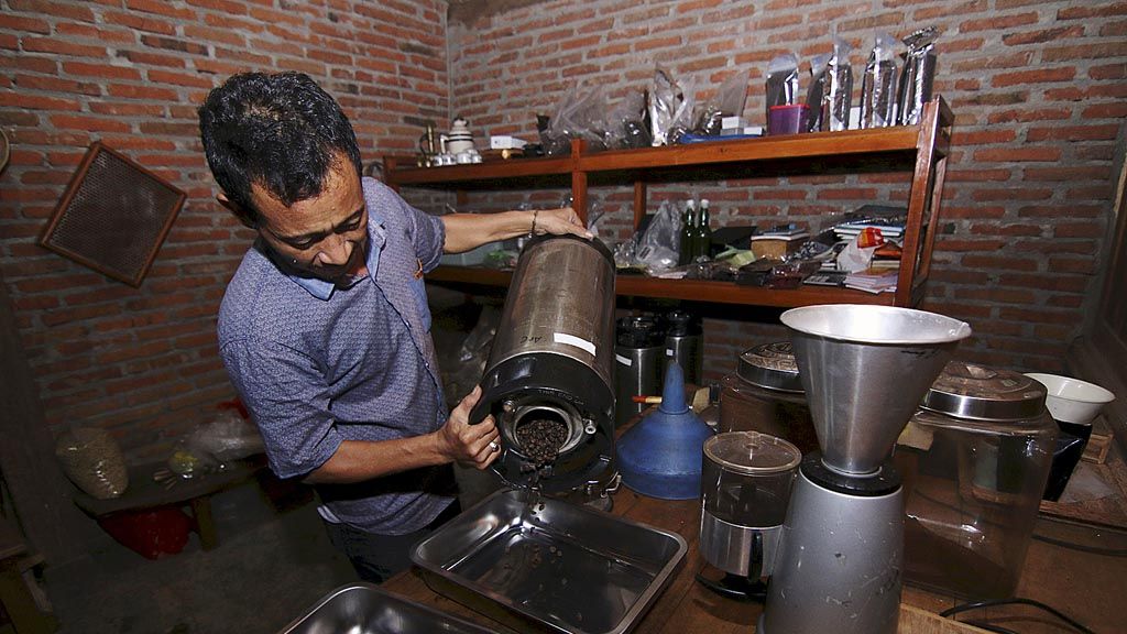 Nidom,  pemilik kedai kopi, mengeluarkan biji kopi untuk disajikan kepada pengunjung di kedai miliknya di Banyuwangi, Jumat (20/10). 