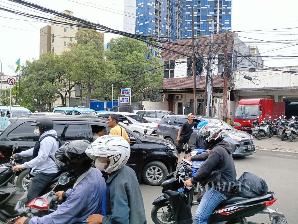 Dua  pak ogah di Jalan Palmerah, Jakarta Barat, saat mengarahkan kendaraan yang putar balik dan menyeberangkan kendaraan lainnya ke arah Jalan Palmerah dari Jalan Palmerah Utara, Jumat (10/2/2023). 