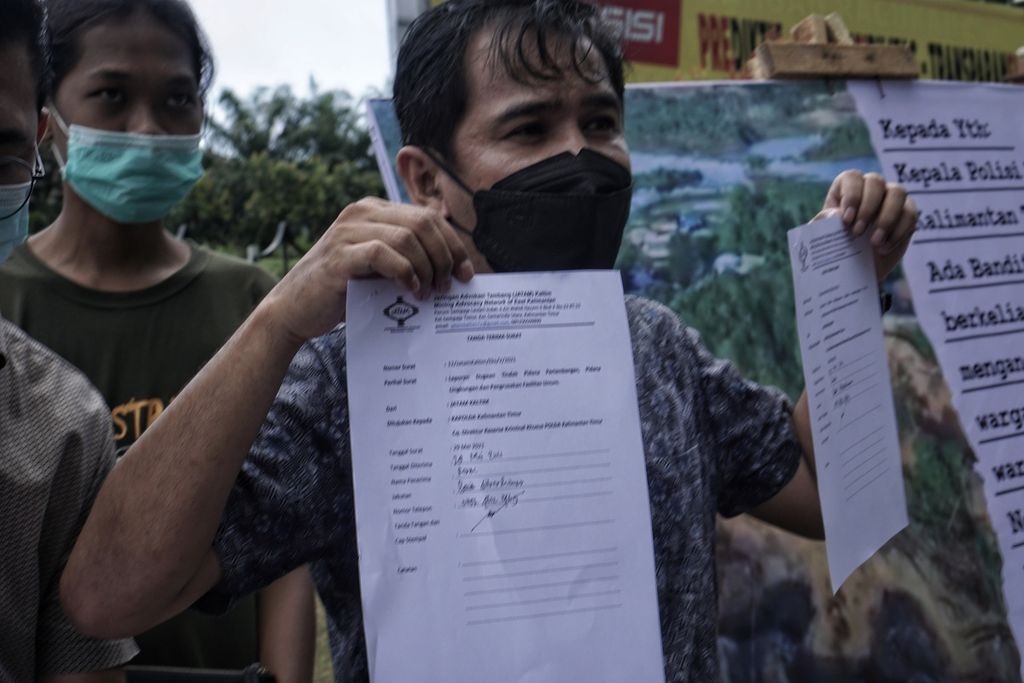 Dinamisator Jatam Kaltim, Pradarma Rupang, menunjukkan surat laporan dalam aksi damai Hari Antitambang 2021 di depan markas Polda Kaltim di Balikpapan, Sabtu (29/5/2021). Dalam aksi tersebut, mereka juga melaporkan sejumlah kasus dugaan tindak pidana pertambangan di Kaltim.