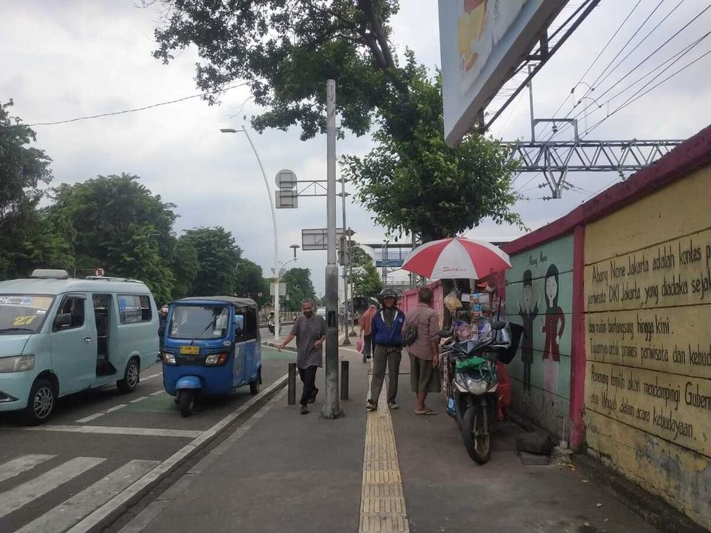 Pedagang kaki lima berjualan di depan mural Stasiun Jatinegara, Rabu (18/1/2023).
