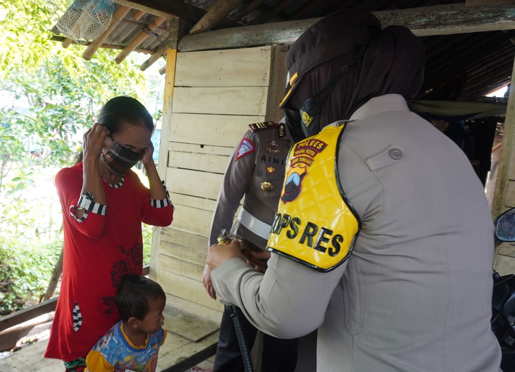 Polisi menyerahkan bantuan bahan pangan dan masker kepada warga terdampak pandemi di Kampung Tirang, Kelurahan Tegalsari, Kecamatan Tegal Barat, Kota Tegal, Jateng (12/2/2021). 