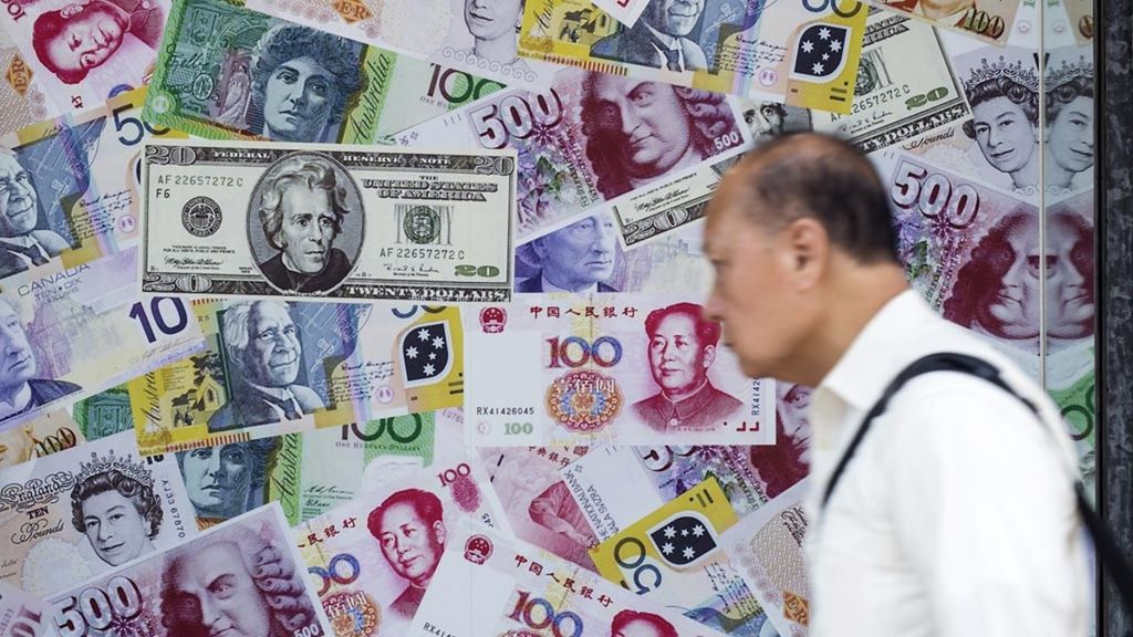 Seorang pria berjalan di depan iklan yang mempromosikan pertukaran uang renminbi (RMB) atau yuan, dollar AS dan euro, pada Agustus 2015 di Hong Kong.  
