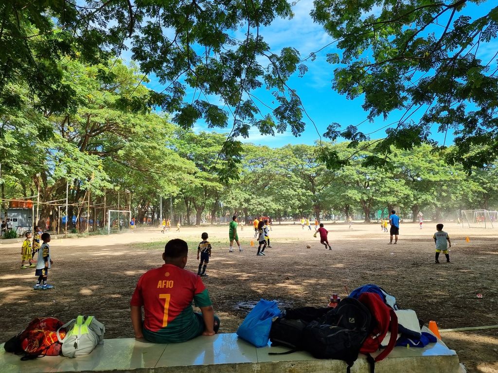 Seorang anak tengah memerhatikan rekan-rekannya bermain sepak bola di Lapangan Karebosi, Minggu (25/6/2023). Impian anak-anak Makassar yang gemar sepak bola adalah membela tim PSM Makassar.