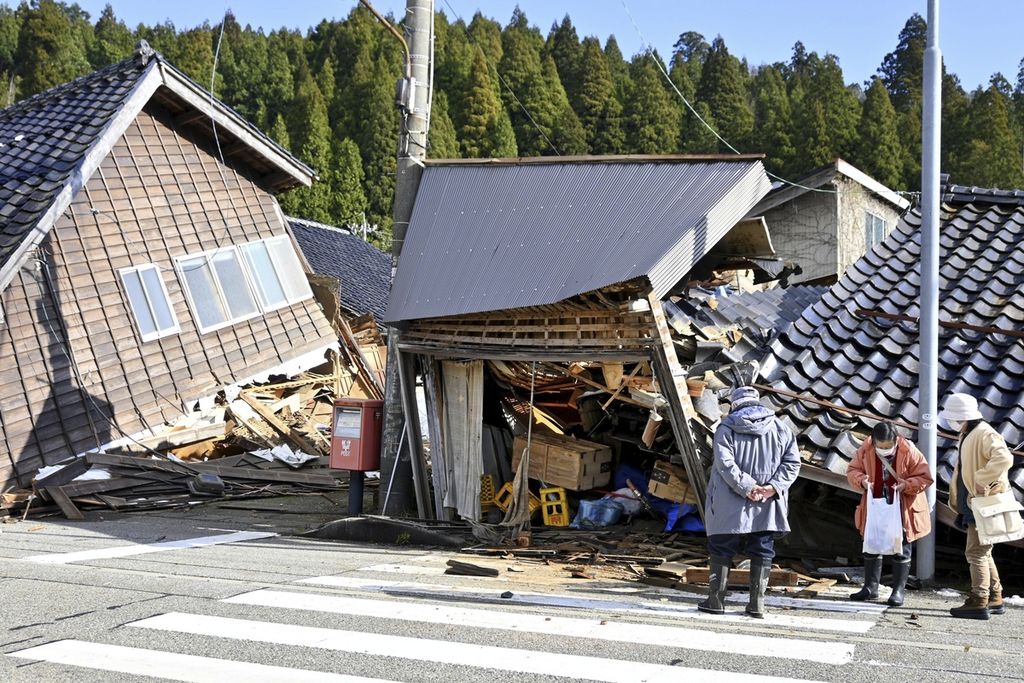 Sejumlah warga yang selamat, Selasa (2/1/2024), melihat bangunan yang roboh setelah gempa berkekuatan M 7,6 mengguncang Prefektur Ishikawa, Jepang, sehari sebelumnya. 