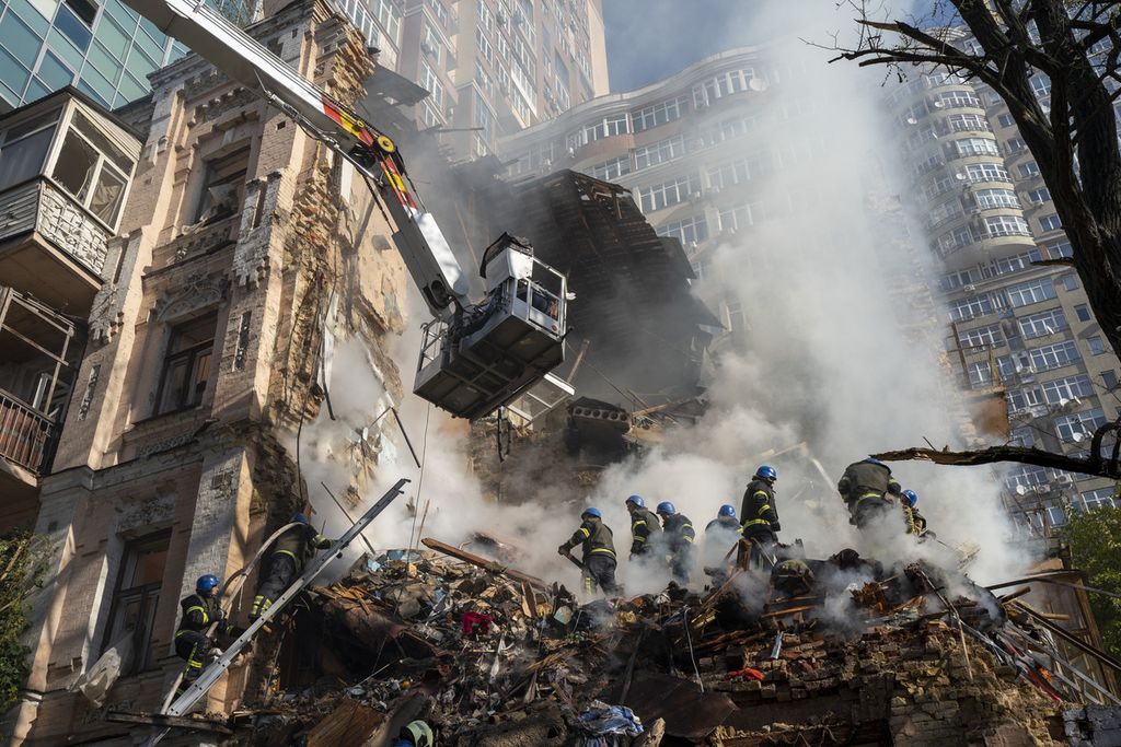 Para petugas pemadam kebakaran bekerja di reruntuhan bangunan yang diserang dengan pesawat nirawak (drone) di Kyiv, Ukraina, Senin (17/10/2022). 