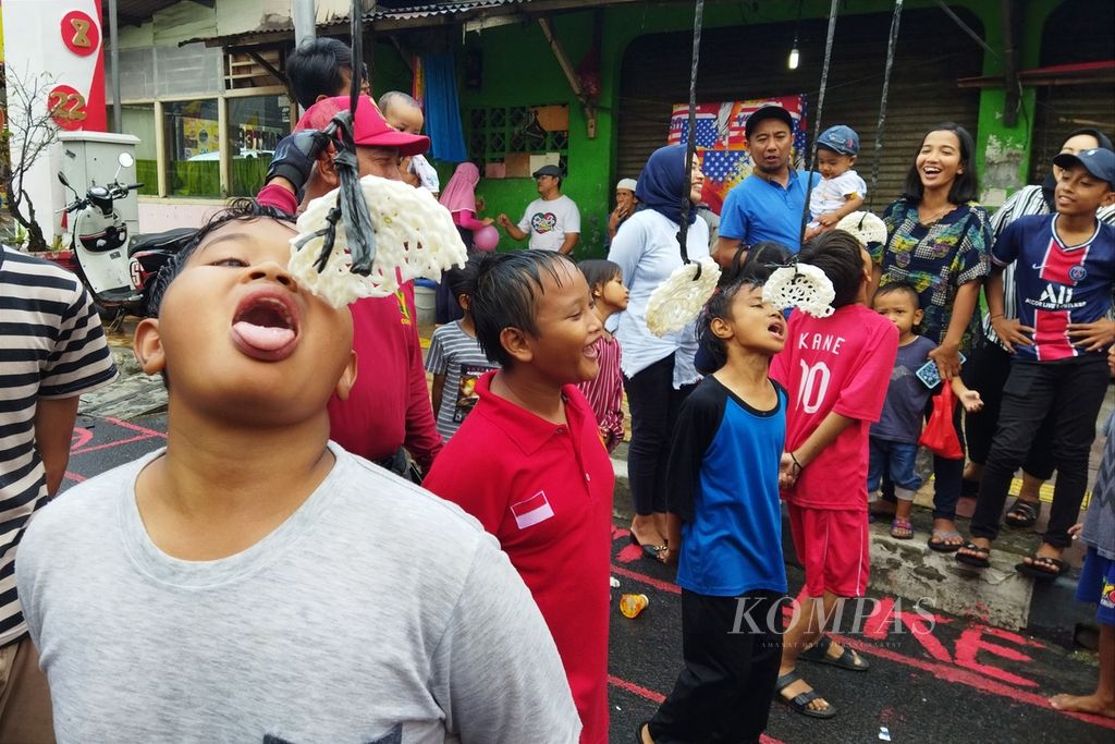 Hujan deras tidak menyurutkan antusiasme dan keceriaan anak-anak di Kelurahan Sukabumi Utara, Kebon Jeruk, Jakarta Barat, mengikuti lomba makan kerupuk, Rabu (17/8/2022). 