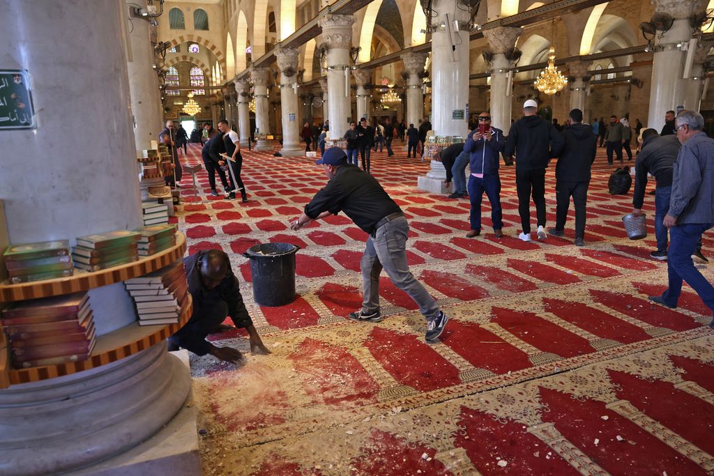 Muslim Palestina membersihkan puing dan kotoran yang ada di atas karpet di dalam ruangan Masjidil Aqsa, Jerusalem, Jumat (15/4/2022), seusai bentrok dengan polisi Israel. 