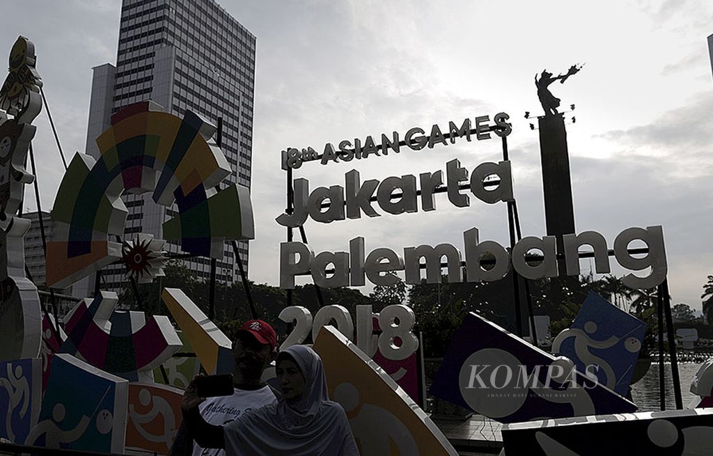Warga berswafoto di depan logo karakter cabang olahraga dan maskot Asian Games 2018 yang menghiasi Bundaran Hotel Indonesia, Jakarta, Minggu (1/10). Pesta olahraga terbesar Asia itu dijadwalkan berlangsung pada 18 Agustus-2 September 2018 di Jakarta dan Palembang.